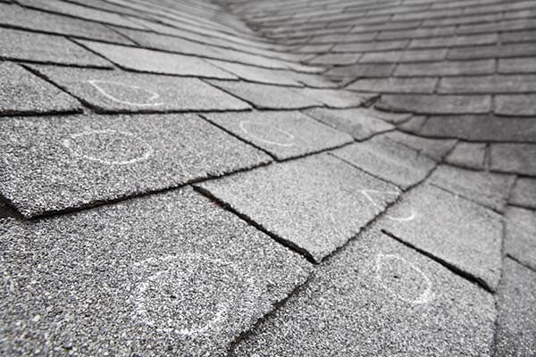Hail damage circled in chalk on an asphalt roof. 