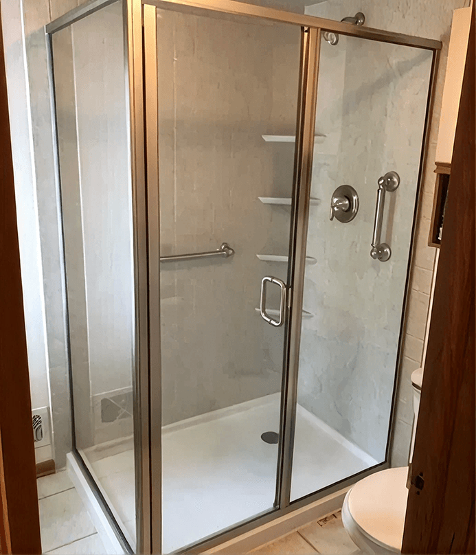 Frameless glass shower enclosure with sliding door and brushed metal hardware in a bathroom corner