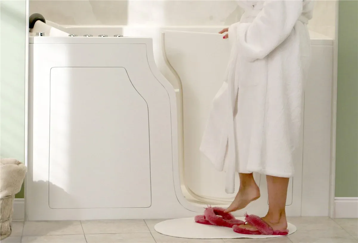 Person in white robe stepping into accessible walk-in bathtub with low entry threshold in modern bathroom
