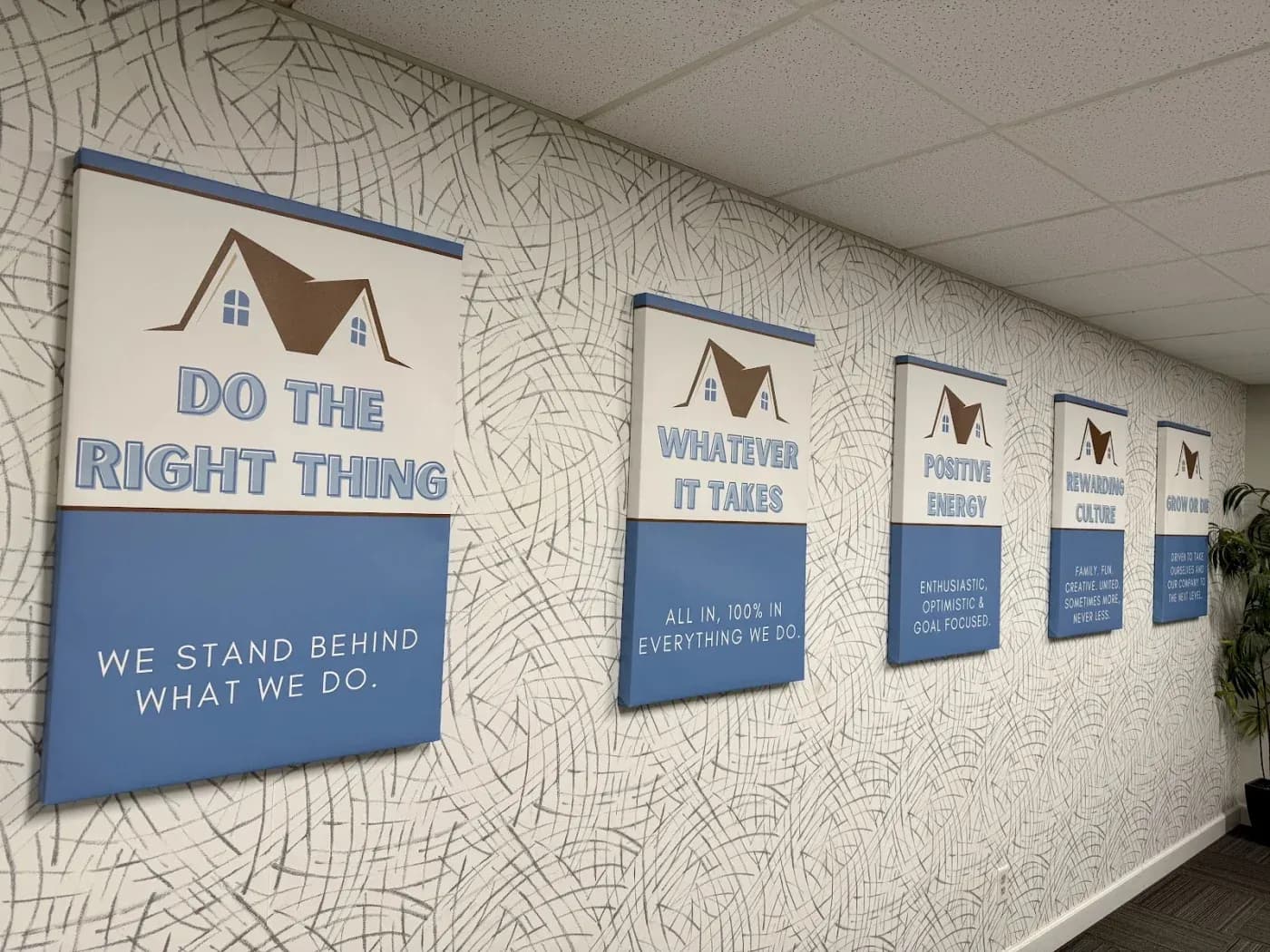 Five mounted signs displaying company values including "Do the Right Thing," "Whatever It Takes," "Positive Energy," "Rewarding Culture," and "Growing Together," each with a house icon and supporting text