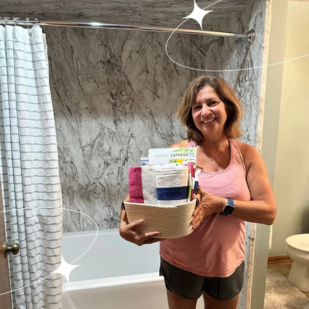 Woman displaying a woven basket filled with rolled towels and a Condo Express box in a bathroom setting