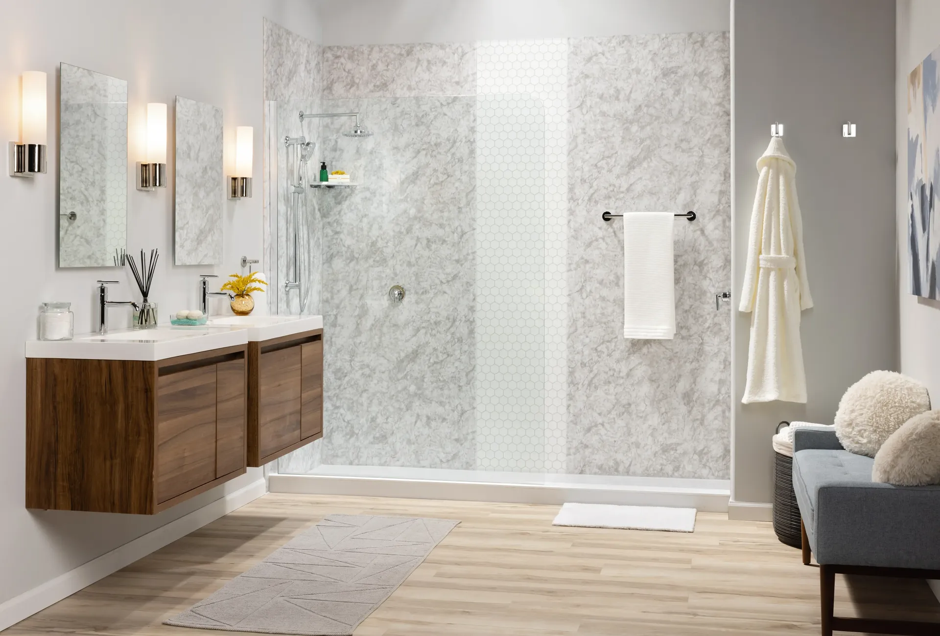 Modern bathroom with walk-in shower featuring marble tile, dual sink vanity with wood cabinets, illuminated mirrors, and spa-like accessories including towel rack and decorative bath items