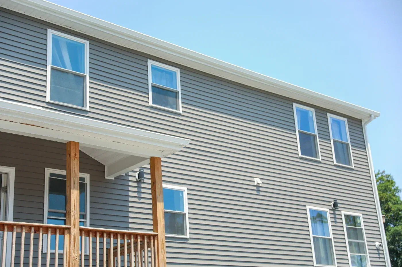 Two-story gray home with horizontal siding, white trim, and multiple replacement windows.