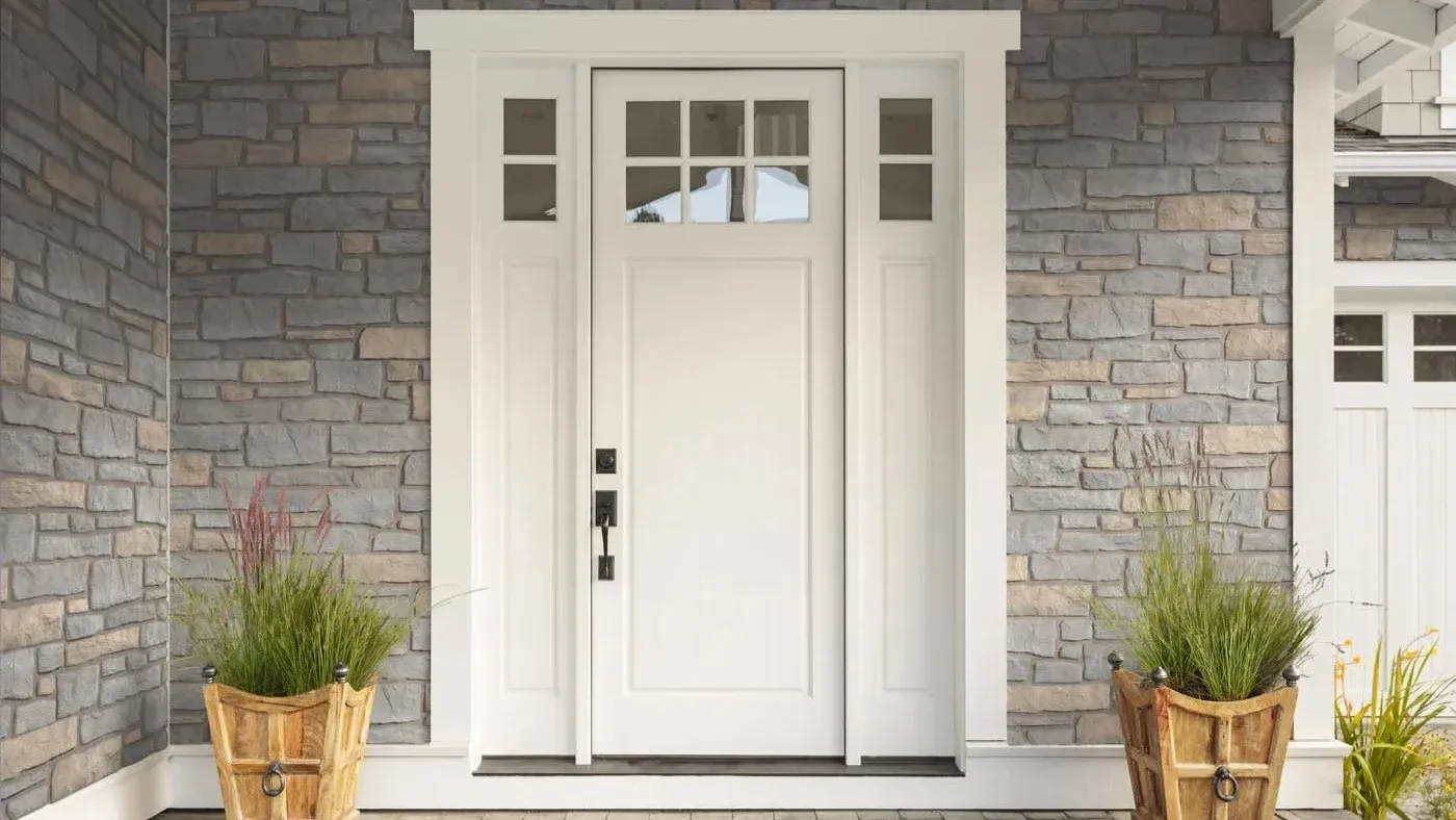 White replacement front entry door with glass panes and matching sidelights set against a stone exterior in Milwaukee, Wisconsin.