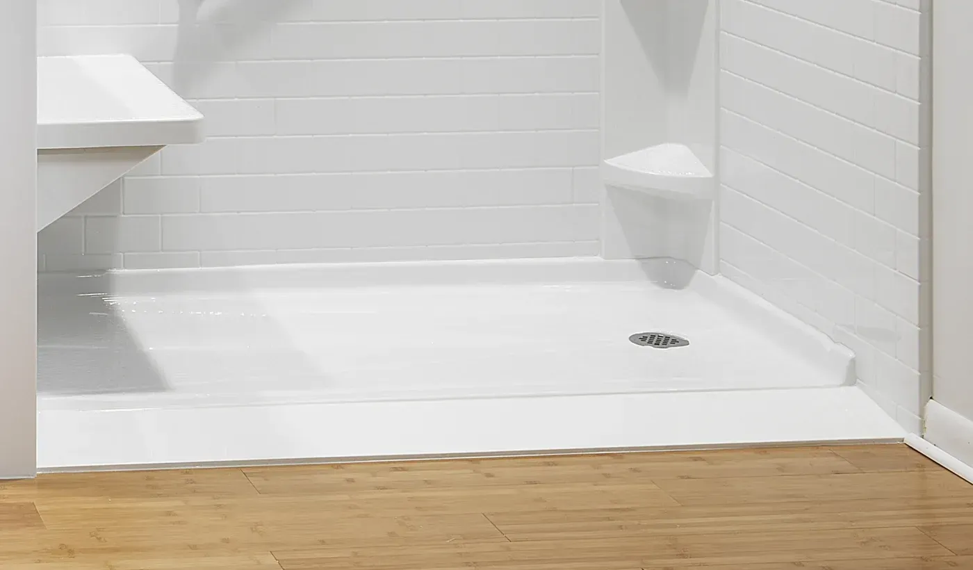 White subway tile shower enclosure with integrated drain and built-in shelving on wood flooring