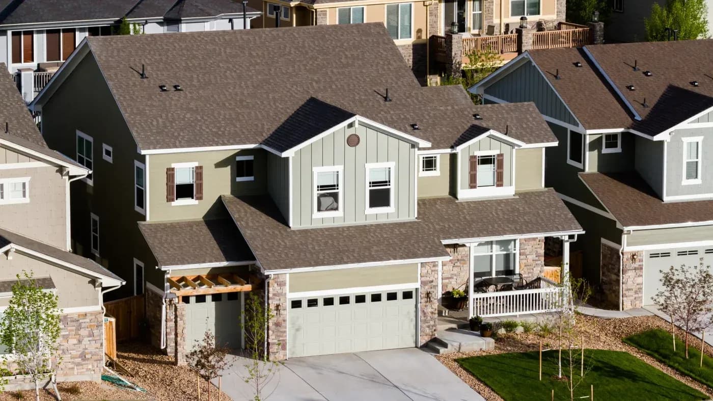 Row of contemporary residential homes with two-car garages, stone accents, and varied exterior colors in a suburban neighborhood