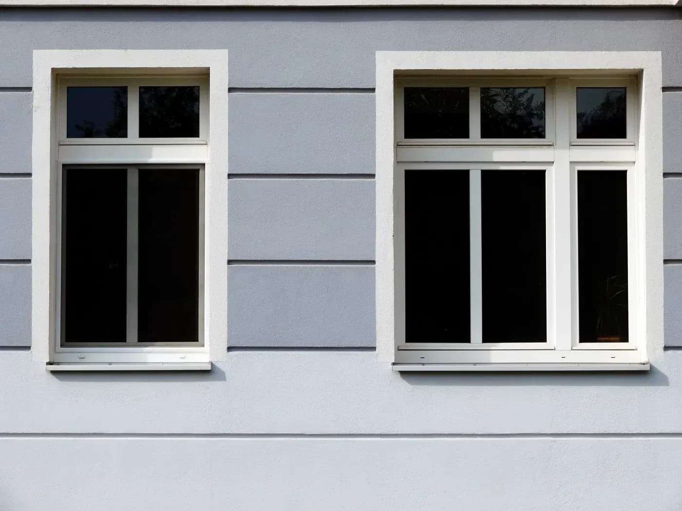 Modern building facade with two sets of white-framed windows on a light blue and gray striped wall