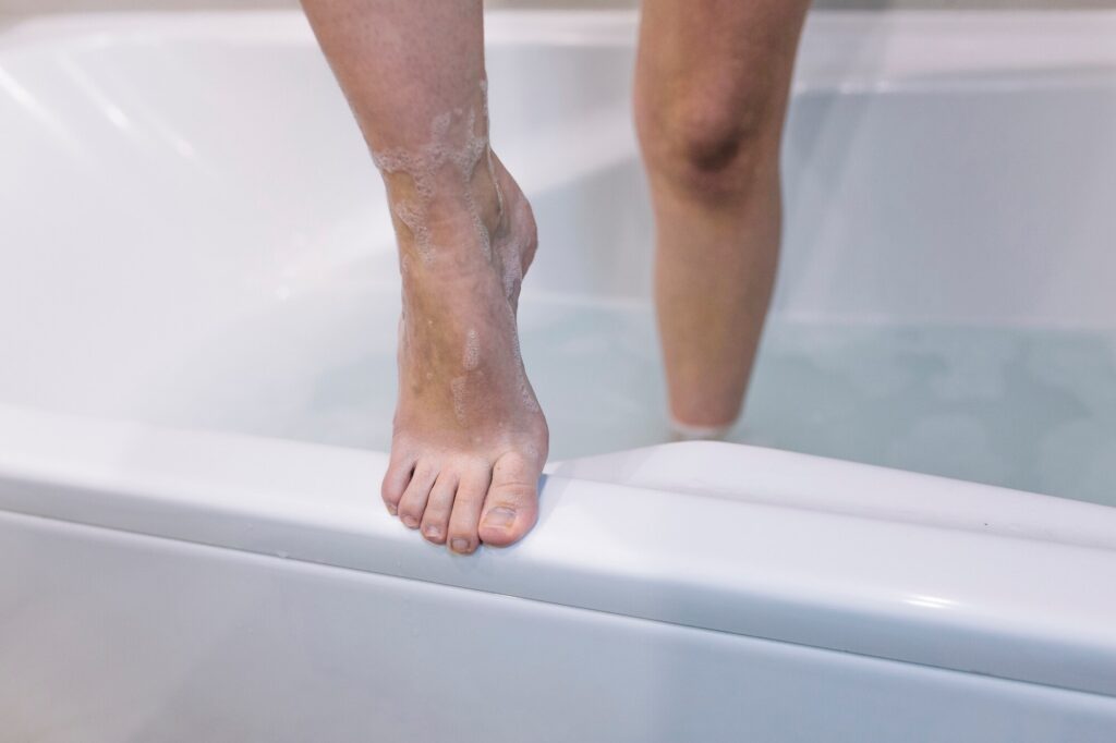 A close-up view of a soapy foot stepping over the threshold of a traditional bath