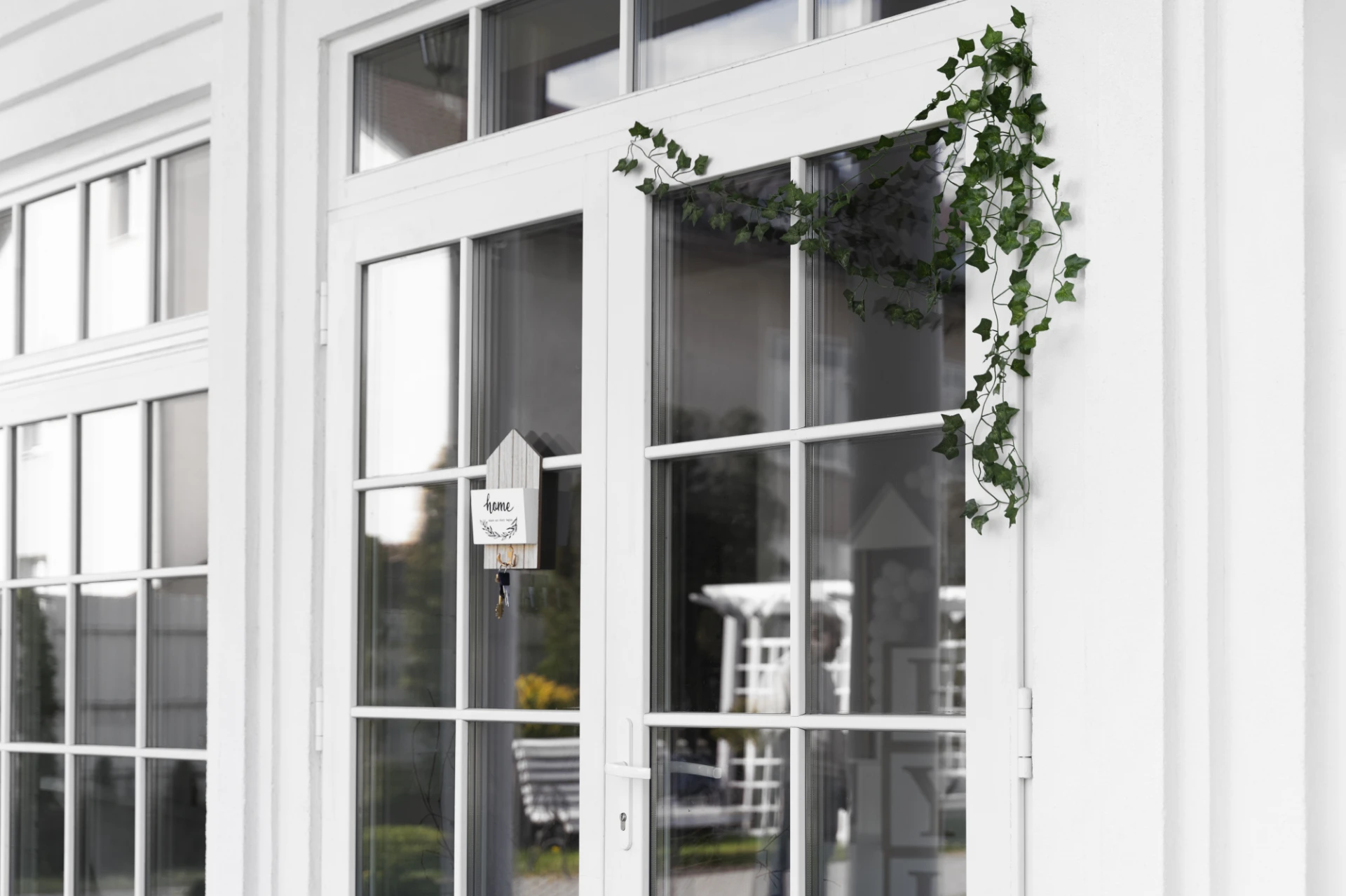 Home restoration near me in Brookfield, WI | Exterior Pros | white house with a white door featuring split-pane windows. A cute, leafy decoration hangs on the side of the door.